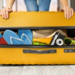 woman closes a full suitcase with things with both hands